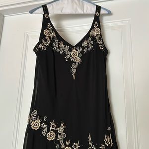 Black cocktail dress with flower embellishments and asymmetrical bottom hem